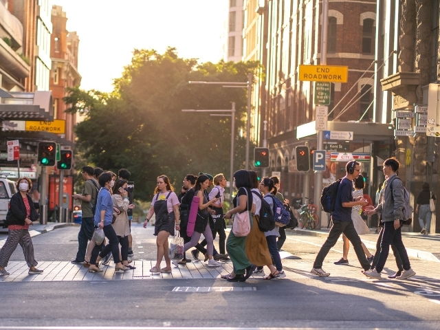A group of people walking on Sydney streets at sunset.