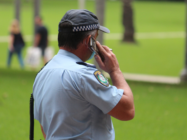 A NSW Police officer makes a mobile phone call. 