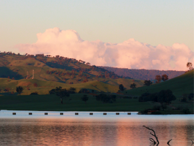 A sunset over lake Hume, with pink clouds reflected in the water.