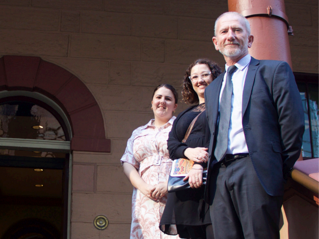 Three people standing in front of Parliament House.