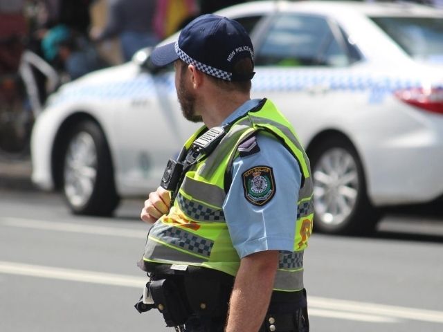 A NSW Police officer wearing a high-vis yellow vest.