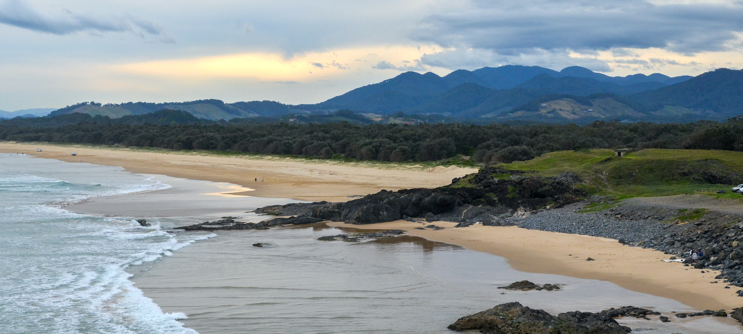 A beach in Gumbaynggirr Country with mountain ranges in the background. 
