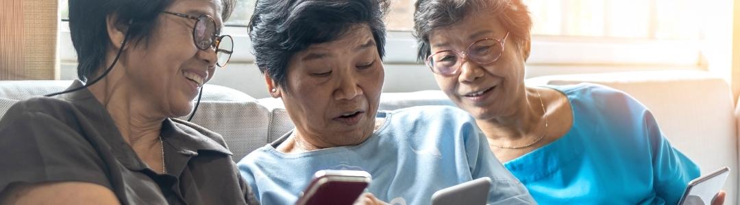 Three older women on the phone laughing together.