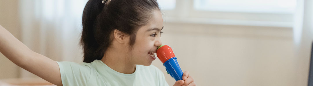 A child laughing and signing into a microphone.