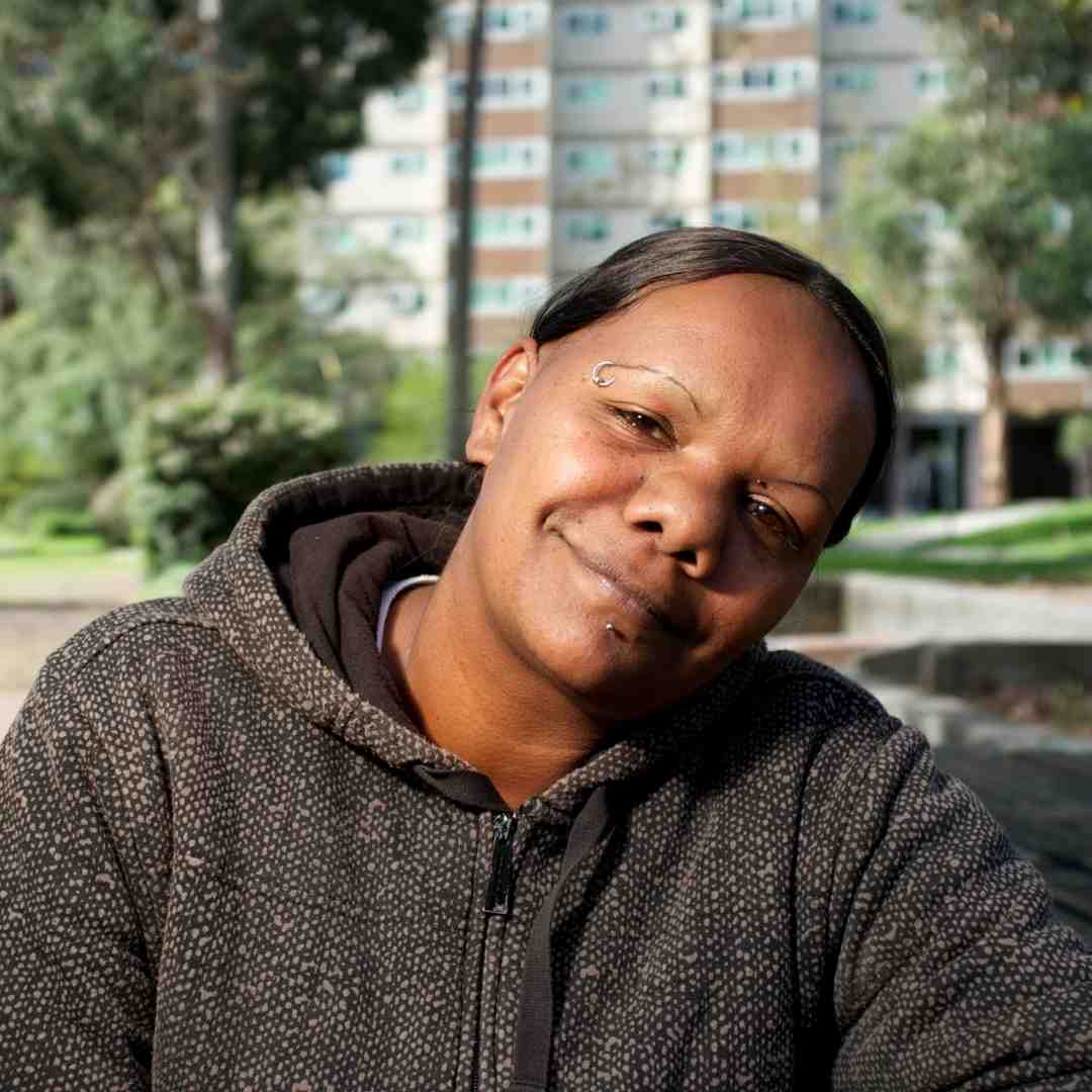 Portrait of a young Aboriginal woman in front of a block of apartments.