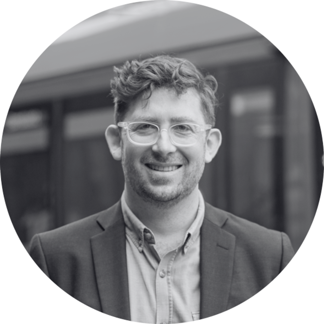 Leo Patterson Ross smiling. He wears glasses and a shirt and blazer.