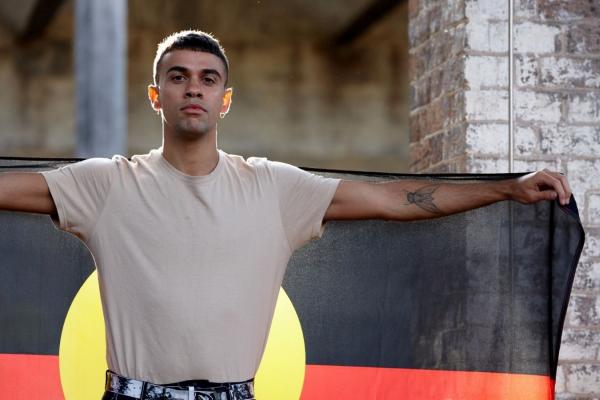 A young man holding an Aboriginal flag.