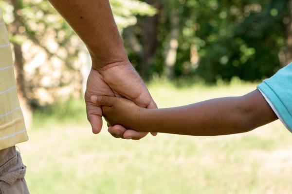 A child and parent hold hands.