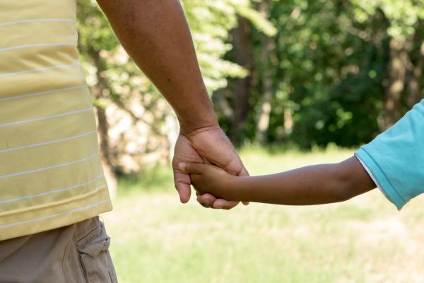 Parent holds a child's hand. 