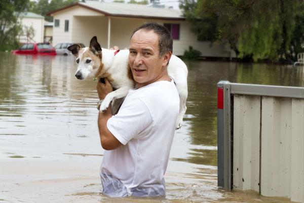 A man holding a dog above flood waters in the Central Coast of NSW.