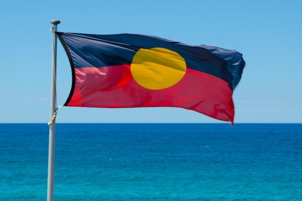An Aboriginal flag flying in front of the ocean. 