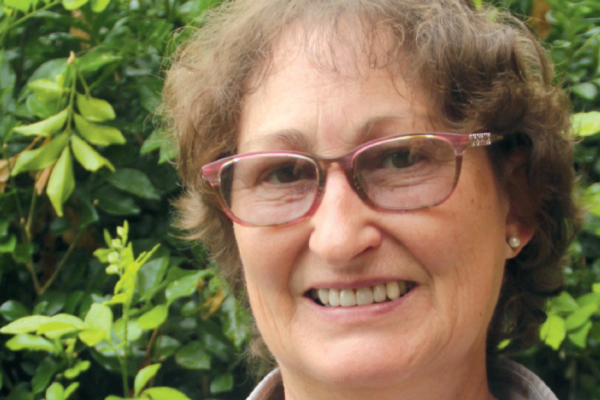 Photo of Helen Campbell smiling slightly in front of a leafy bush