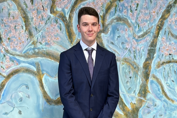 CLCNSW First Nations cadets Jai McGaw smiling outside the Downing Centre in front of a painting of flowering trees